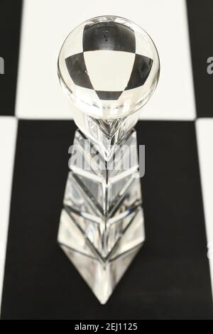 Boule de verre sur un socle en cristal avec réfraction de carreaux noirs et blancs Banque D'Images