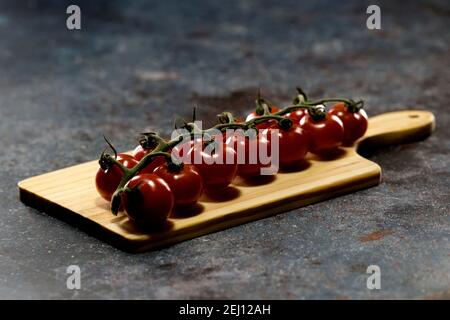 Les tomates britanniques Piccolo qui se trouvent sur la planche à découper sont de grande saveur, de belle couleur et de petite taille Banque D'Images