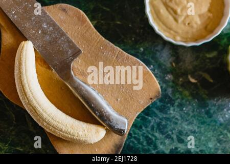 La banane sans pelage sur une planche à découper en bois, vue de dessus Banque D'Images