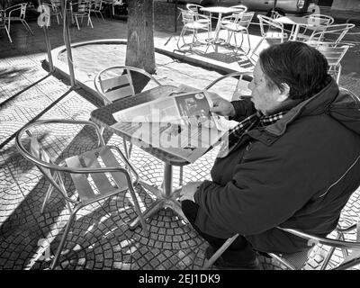 SYRACUSE, ITALIE - JENUARY 03: Un homme avec un cigare est assis dans un café en plein air et lit un article de presse. Tourné en 2015 Banque D'Images