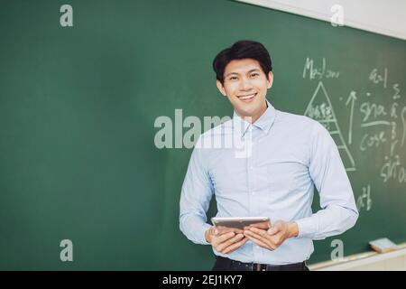 jeune professeur souriant debout devant le tableau noir Banque D'Images