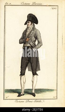 Dandy français en tenue semi-formelle. Chapeau Bicorne, manteau gris, gilet ou gilet blanc, culottes et boyaux, chaussures à boucle. Costume demi-habillé. Gravure en plaque de coperplate de couleur main par Pierre-Charles Baquoy d'après Carle Vernet du Journal des Dames et des modes de Pierre de la Mesangère, Magazine des femmes et de la mode, Paris, an 11, 1803. Banque D'Images