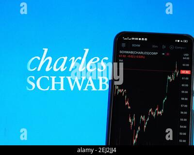 Dans cette photo illustration les informations boursières de Charles Schwab Corporation s'affiche sur un smartphone tout en affichant le logo de Charles Schwab Corporation s'affiche en arrière-plan Banque D'Images