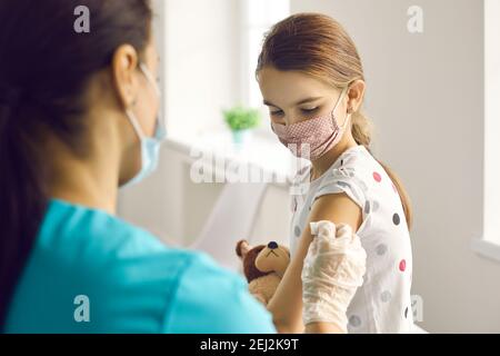 Femme médecin mettant le plâtre médical à la fille patients bras après vaccination Banque D'Images