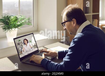 Homme utilisant son ordinateur portable, appréciant la visite virtuelle à la clinique et de consulter un médecin en ligne Banque D'Images
