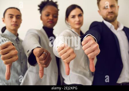 Groupe de jeunes gens d'affaires qui donnent des pouces vers le bas pour montrer leur aversion pour le mauvais travail Banque D'Images