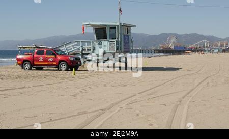 SANTA MONICA, LOS ANGELES CA USA - 28 OCT 2019: Esthétique de plage d'été de Californie. Tour de guet en bois bleu emblématique, voiture de sauvetage rouge sur sable ensoleillé Banque D'Images