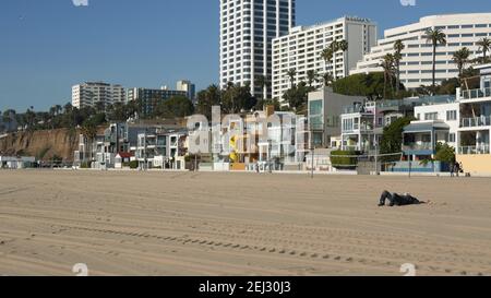 SANTA MONICA, LOS ANGELES CA USA - 19 DEC 2019: Seul l'homme anonyme ressemble à des chômeurs et sans-abri dormant sur le sable de la plage. Sans-abri et mendicité Banque D'Images