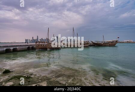 Vue panoramique de Doha depuis la promenade de la corniche l'après-midi Montrant des huws avec le drapeau du Qatar dans le golfe arabe à premier plan Banque D'Images