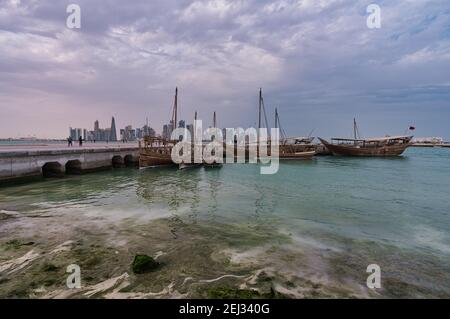 Vue panoramique de Doha depuis la promenade de la corniche l'après-midi Montrant des huws avec le drapeau du Qatar dans le golfe arabe à premier plan Banque D'Images