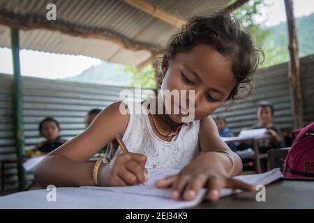 Pokhara, Népal. 09-15-2017. Fille d'un village dans les montagnes du Népal écrivant pendant la classe lors de la fréquentation scolaire. Banque D'Images