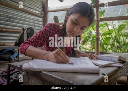 Pokhara, Népal. 09-15-2017. Fille d'un village dans les montagnes du Népal écrivant pendant la classe lors de la fréquentation scolaire. Banque D'Images