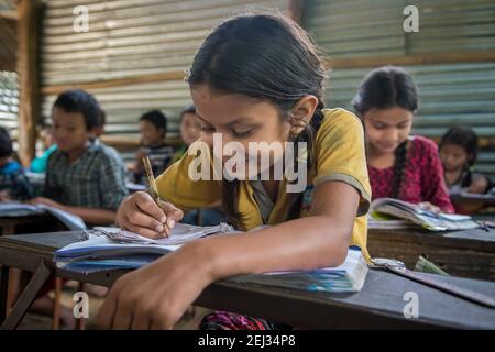 Pokhara, Népal. 09-15-2017. Fille d'un village dans les montagnes du Népal écrivant pendant la classe lors de la fréquentation scolaire. Banque D'Images