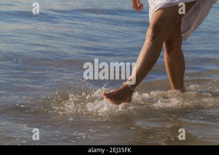 Gros plan des pieds féminins avec la cheville jouant dessus eau de mer Banque D'Images