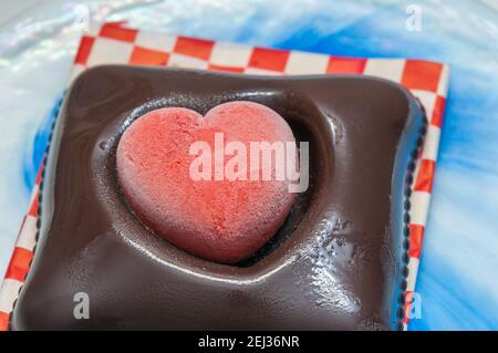 Glace végétalienne pour la Saint-Valentin, chocolat et fraise, forme de coeur, sur une assiette en verre Banque D'Images