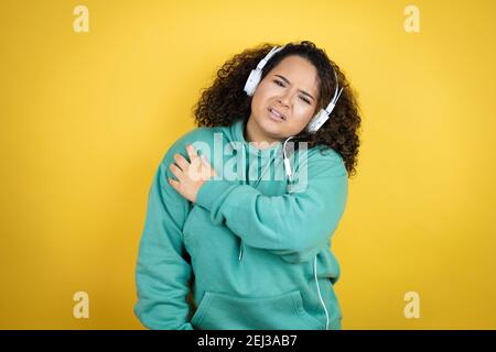 Jeune fille afro-américaine portant des vêtements de sport et utilisant des écouteurs avec une douleur sur son épaule et une expression douloureuse Banque D'Images