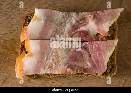 Sandwich de pain noir et de saindoux salé avec des lanières de viande, sur une planche de bois Banque D'Images