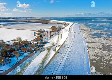 Aérienne du village enneigé de Moddergat à la mer gelée de Waddensea En hiver aux pays-Bas Banque D'Images