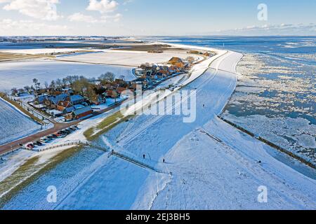 Aérienne du village enneigé de Moddergat, en Frise, à un état gelé Waddensea aux pays-Bas en hiver Banque D'Images