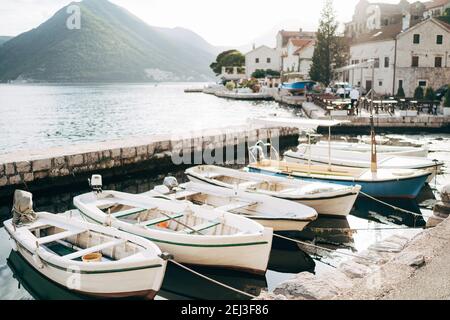 Des bateaux de pêche en bois amarrés au rivage sur fond de montagnes et de maisons à Perast, au Monténégro. Banque D'Images