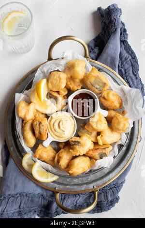 Vue en hauteur d'un délicieux tempura de merlu sur un plateau circulaire avec curry et sauces barbecue au milieu. Banque D'Images