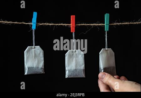 Sachets de thé blanc isolés sur fond tenant sur la corde, choisissez-en un à la main. Sélectionnez le meilleur concept. Meilleur choix de thé Banque D'Images