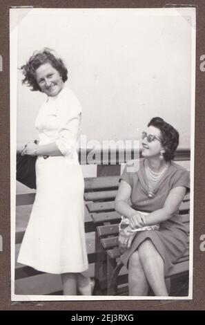 Photo noir et blanc vintage de deux femmes assis sur un banc pendant les vacances des années 1930. Banque D'Images