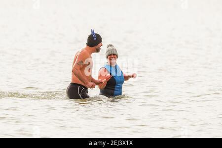 New Forest, Hampshire. 21 février 2021. Météo Royaume-Uni. Un couple piquez une tête lors d'une journée de plongée chaude et lumineuse à la plage de Calshot dans la Nouvelle forêt. Credit Stuart Martin/Alay Live News Banque D'Images