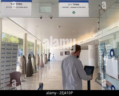 Tel Aviv, Israël. 21 février 2021. Un homme utilise un écran avec logiciel de reconnaissance faciale à l'entrée pour entrer à la réouverture du Théâtre national de Habima. En Israël, toute personne qui a récupéré, ainsi que toute personne qui a été vaccinée, peut obtenir une carte de vaccination en ligne une semaine après leur deuxième vaccination. Les salles de sport, les institutions culturelles et les piscines peuvent être à nouveau visitées. Toutefois, cela ne s'applique qu'aux titulaires d'un passeport vert pour les personnes vaccinées et convalescentes. (À dpa 'Israël commence l'utilisation de Green Pass pour Corona vacciné') Credit: Sara Lemel/dpa/Alamy Live News Banque D'Images