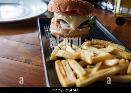 Hamburger savoureux avec frites sur table en bois Banque D'Images