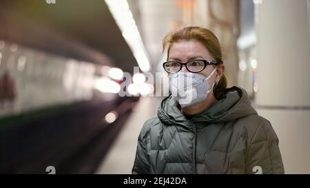 Femme mature dans un masque respiratoire en attente de train à la plate-forme de la station de métro. Concept de nouvelle réalité de la vie pendant la pandémie de COVID 19 Banque D'Images