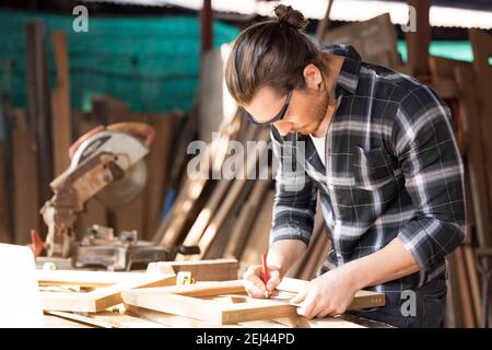 Menuisier travaillant sur machines à bois en atelier de menuiserie. Un homme travaille dans un atelier de menuiserie. Banque D'Images