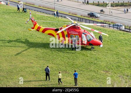 Southend on Sea, Essex, Royaume-Uni. 21 février 2021. L'ambulance aérienne Essex & Herts AgustaWestland AW169 enregistrement de l'hélicoptère G-HHEM débarqua sur les Cliff Gardens au-dessus de l'Esplanade occidentale sur le front de mer de Southend. Il a attiré des gens qui étaient dehors appréciant le temps chaud et ensoleillé de façon insaisonnière Banque D'Images