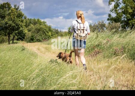 Randonnée pédestre femme marchant avec son chien dans la nature à l'été. Touriste avec sac à dos en profitant de la marche avec son animal meilleure amie Banque D'Images