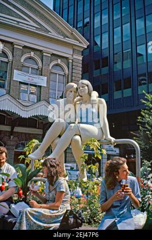 Une sculpture de 1991, «The Whisper», d'André Wallace, installée parmi les employés de bureau à l'extérieur de la gare de Fenchurch Street, Londres, Angleterre, Royaume-Uni 1993. Les grandes figures féminines sont peintes mais Wallace a créé des versions de l'œuvre en bronze aussi. Cette œuvre faisait partie de l’« Art in the City » de 1993 et visait à faire de la sculpture une place parmi les espaces verts et l’architecture distinctive de la City de Londres. André Wallace (1947) est un sculpteur et artiste travaillant dans le bronze, la pierre, la résine translucide et divers métaux et produit également des œuvres sur papier. Il travaille souvent à grande échelle. Banque D'Images