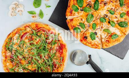 Une vue de dessus de délicieuses pizzas avec du fromage fondu, des champignons, des épinards, et des arugula sur la table Banque D'Images