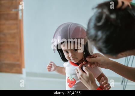 Le Bebe Porte Un Casque De Moto Lorsqu Il Est Attache Par Son Mere Sur La Moto Photo Stock Alamy