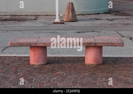 Un banc de béton rose isolé sur un trottoir pavé (Pesaro, Italie, Europe) Banque D'Images