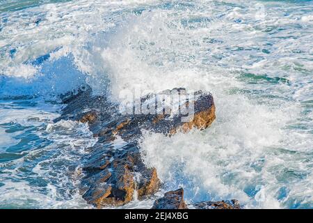 Image en gros plan des vagues blanches capturées dans mouvement contre les rochers Banque D'Images