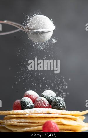 Verser du sucre sur des crêpes faites maison sur une table, photographie de nourriture sombre Banque D'Images