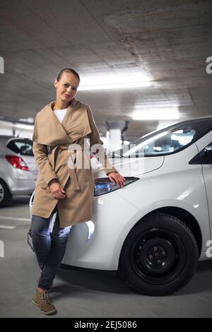 Parking/garage souterrain (DOF peu profond; image colorée) - jeune femme avec sa voiture dans le parking souterrain Banque D'Images