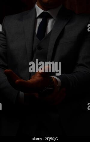 les mains de sexe masculin ferment, le marié se prépare le matin avant la cérémonie de mariage. L'homme règle une montre sur sa main sur un arrière-plan sombre 2021. Banque D'Images