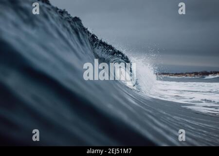 Des vagues parfaites avec de l'eau bleue ciel sombre nuageux. Banque D'Images
