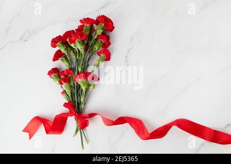 Fleurs de la carnation béaytiful avec ruban rouge sur fond de marbre. Vue de dessus Banque D'Images