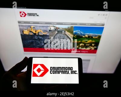 Personne tenant un smartphone avec le logo de l'entreprise minière américaine Drummond Company Inc. À l'écran devant le site Web. Mise au point sur l'affichage du téléphone. Banque D'Images