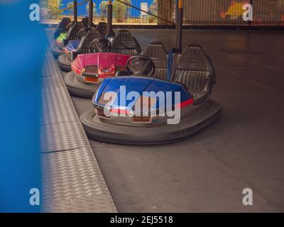 Voitures pare-chocs électriques colorées à l'ancienne pour deux dans un parc d'attractions de la ville. Divertissement familial traditionnel et loisirs actifs. Banque D'Images