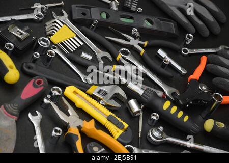 Kit d'outils pour homme à main sur table en bois noir. Beaucoup de clés et de tournevis, pilers et autres outils pour tout type de réparation ou de construction. Réparation Banque D'Images