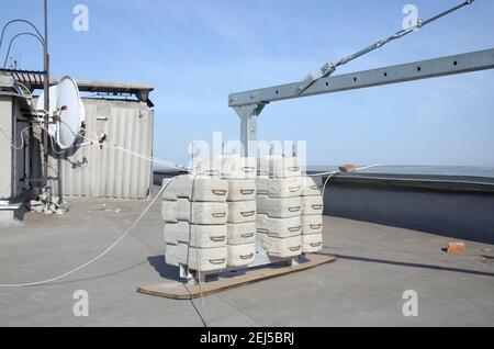 Contrepoids ou contrepoids blocs de béton ou briques en tant que partie de la plate-forme de corde de fil suspendu pour les travaux de façade sur de hauts bâtiments à plusieurs étages. Homme Banque D'Images