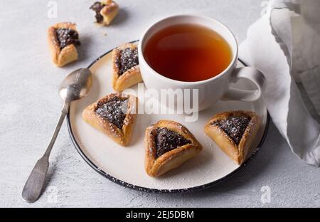 Biscuits faits maison au hamantashen (oreilles de Haman) avec graines de pavot et pommes sur fond gris clair. Pâtisseries traditionnelles pour Purim, carnaval juif Banque D'Images