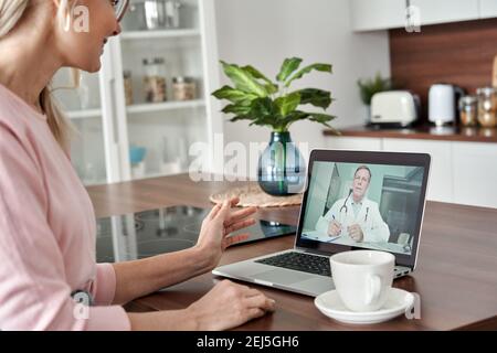 Patiente d'âge moyen qui obtient une consultation en ligne par télémédecine à domicile. Banque D'Images